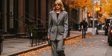 Celebrity in chic fall street style outfit, tailored blazer, wide-leg trousers, city backdrop