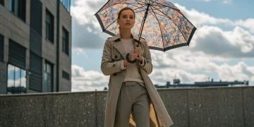 Woman in layered trench coat, knit, and trousers for changing weather