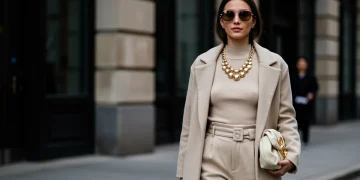 Woman in stylish outfit accessorizing with statement necklace and sunglasses